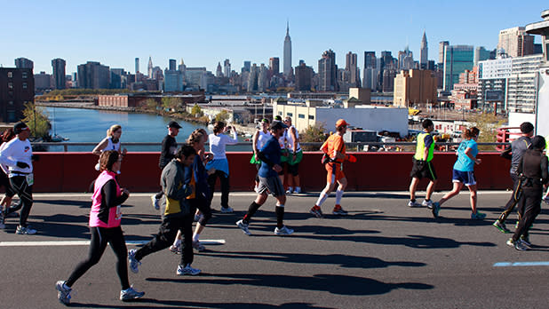 Runners participate in the TCS New York City Marathon with a view of the Empire State Building in the distance