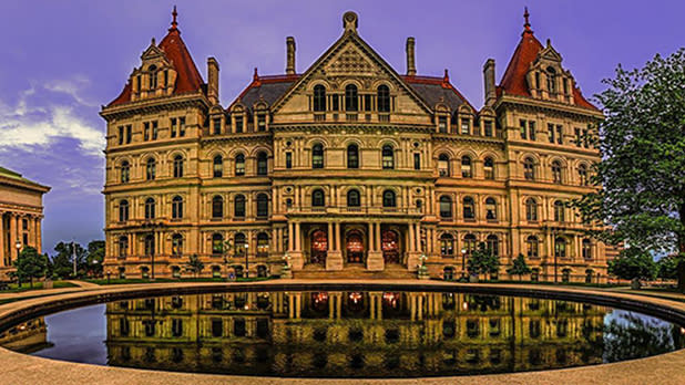 The New York State Capitol with a fountain in front of it reflecting its image