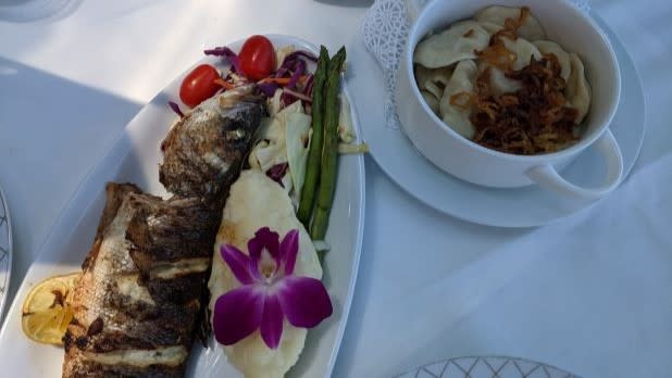 A plate with grilled fish and vegetable and a bowl of Siberian Pelmeni dumplings from Tatiana in Brighton Beach NYC