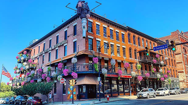 A 4-story corner brick building with flowers on the exterior o