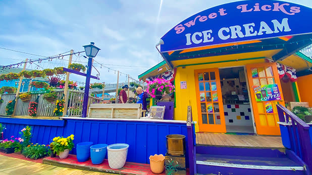 A lively ice cream shop adorned with bright colors and a prominent sign that says "Sweet Lick's Ice Cream."