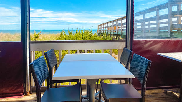 A table and chairs set on a deck, providing a scenic view of the ocean in the background at Sand Castle on the Ocean.