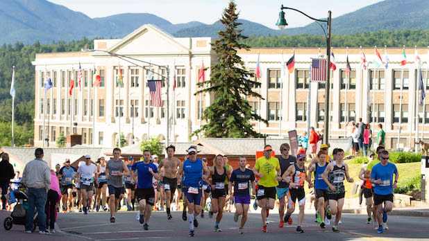 people running on the street in the Lake Placid Marathon with the Olympic Center in the background