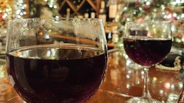 Two glasses of red wine surrounded by bright holiday lights