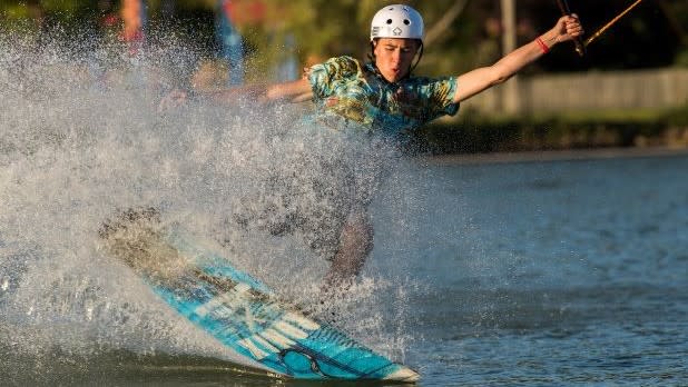 A person wearing a white helmet while riding a wakeboard at Roseland Wake Park