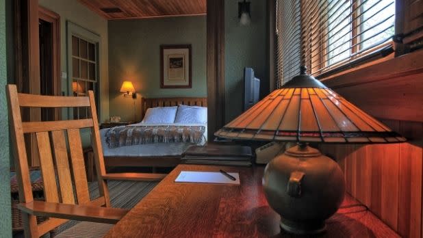 A table and lamp, plus a bed, in a room at Roycroft Inn