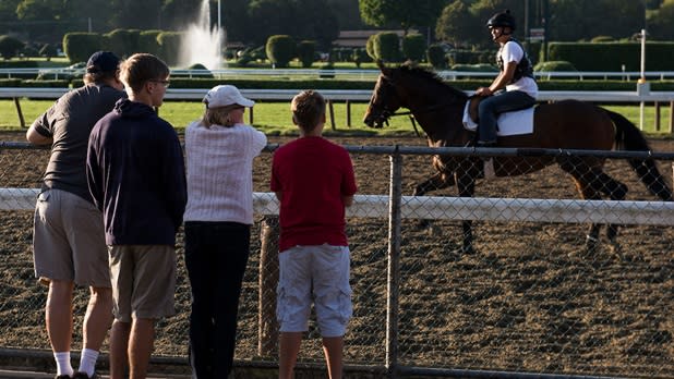 A family of four watches a horse and jockey from the fences at the Saratoga Race Track