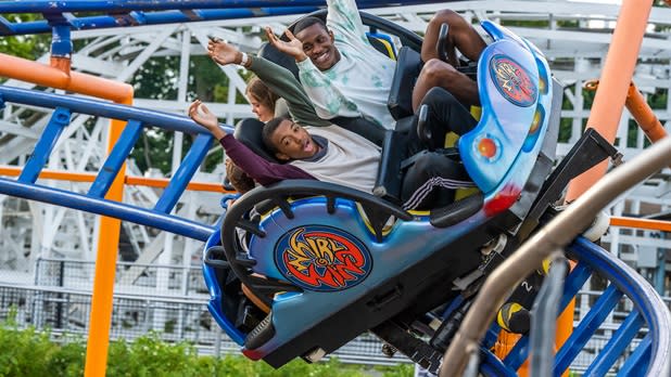 Two teens put their arms up as they zoom on a rollercoaster at Seabreeze