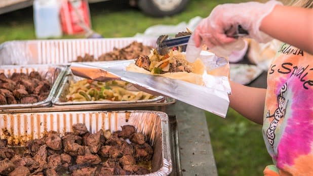 A woman stuffs a roll with meat and sautéed vegetables at the Spiedie Fest & Balloon Rally