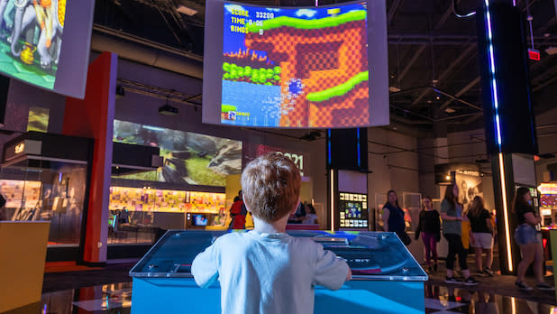 a child looks up at a large projection screen while playing a video game at the National Museum of Play at the Strong in Rochester, NY