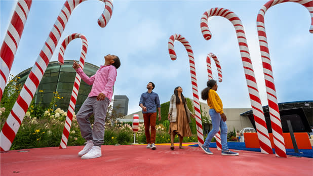A family walks through giant candy canes