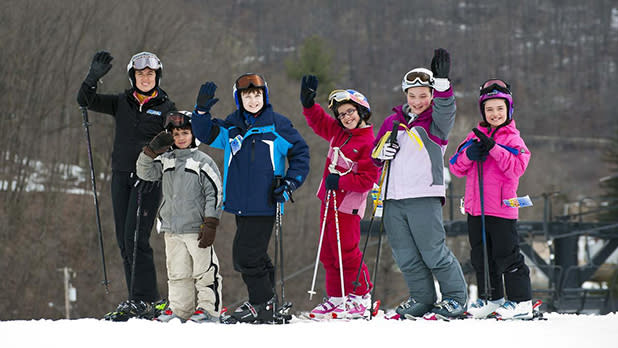 A group of skiers smile and wave at the camera while on the slopes at Swain Resort