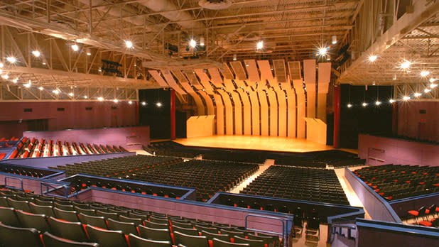 Rows of tiered red seats face a theater stage at the Tilles Center for the Performing Arts