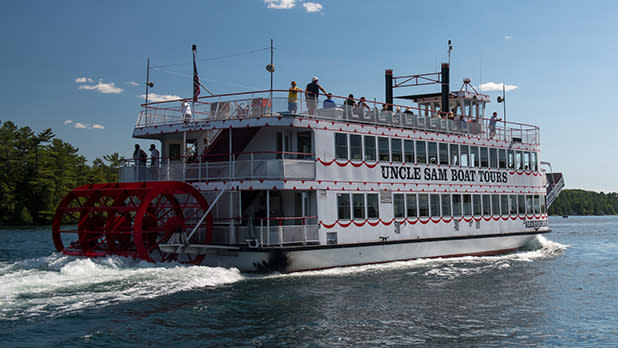 A red and white steamboat with a red paddlewheel and the name, Uncle Sam Boat Tours, painted on the side.