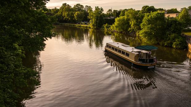 A tour boat floats down the canal at sunset