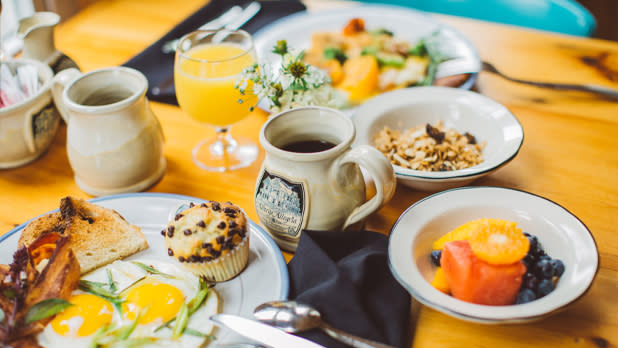 A breakfast spread with eggs, toast, fruit, tea, and orange juice