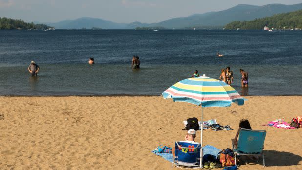 Umbrella over beach chairs on sandy beach next to Lake George