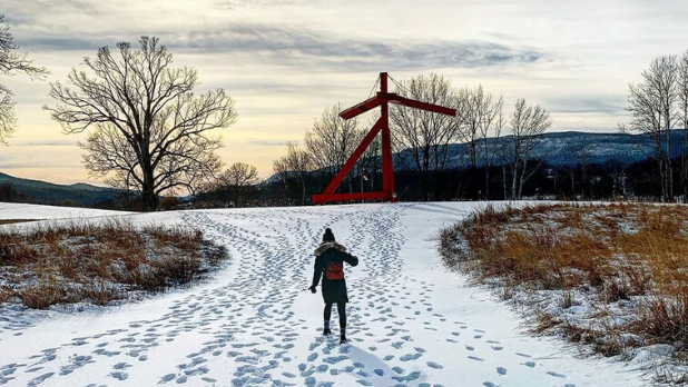 A photo of a woman walking up to a sculpture at Storm King Art Center in the winter