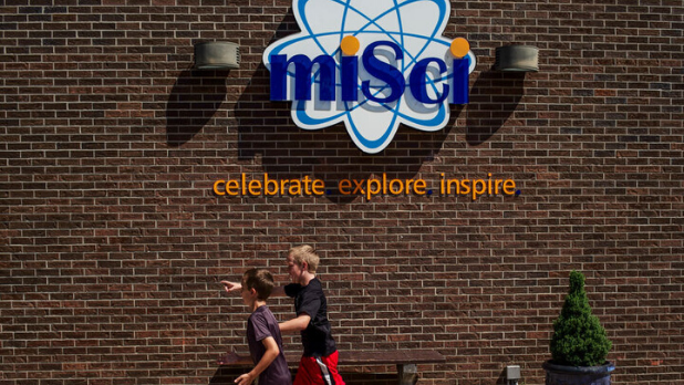 A photo of two children running under the miSci (the Museum of Innovation and Science) sign
