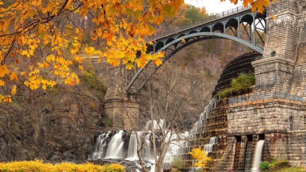 Colorful fall foliage surrounding a bridge and rushing dam