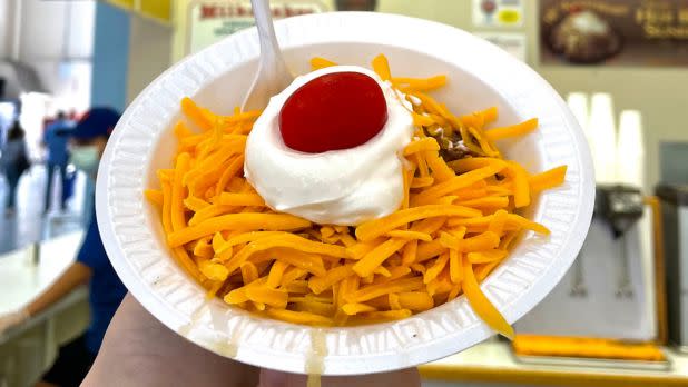 Bowl of meat covered in shredded cheese, sour cream, cherry tomato