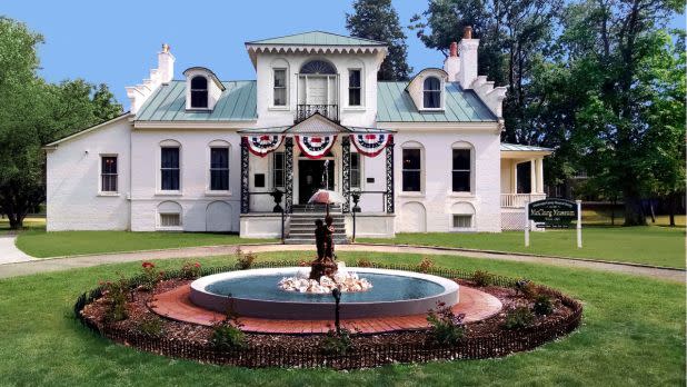 Exterior of museum with a fountain in front surrounded by flowers