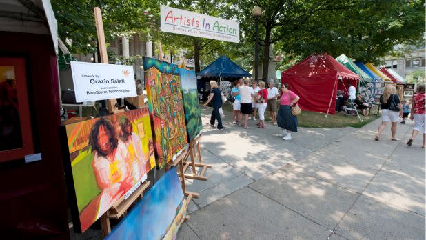 Art on display outdoors, people wandering around