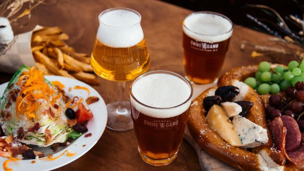 Table with full glasses of beer, fries, and plates full of food