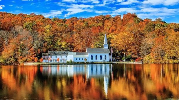 Colorful fall foliage on trees reflecting over a body of water