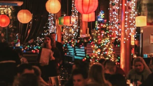 Dimly lit cafe and lounge filled with bright, festive lights and people dining