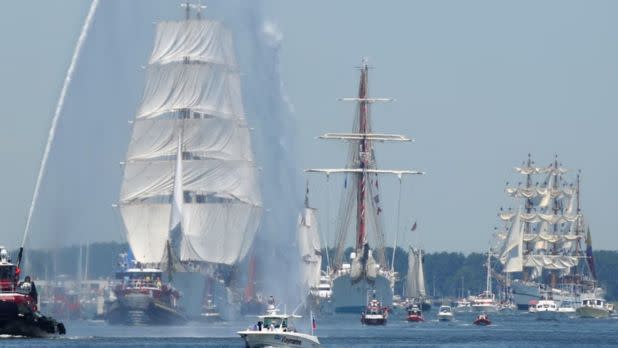 A number of historic sailboats sailing on the water