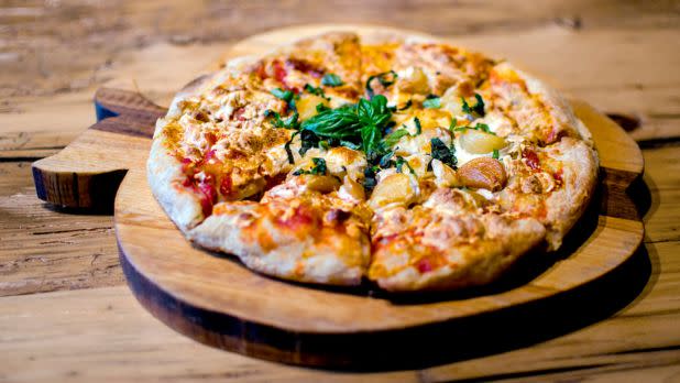 Artisan pizza on an apple shaped wooden board