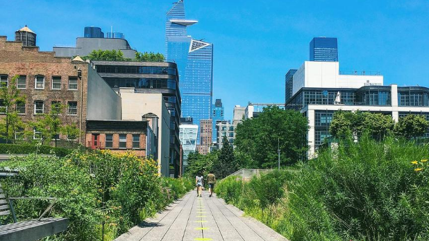 A sunny day on The High Line with two people walking in the distance