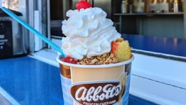 A cup of frozen custard topped with whipped cream, nuts, and a cherry