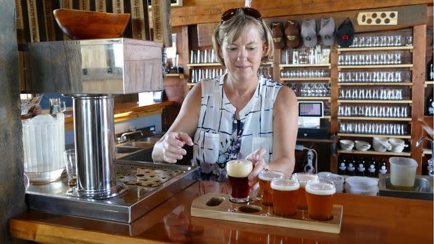 Woman standing behind bar pouring beer