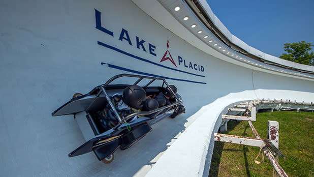 A group of people in helmets race down a bobsled track in Lake Placid