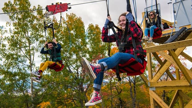 Two people zoom down the skyflyer zipline side by side