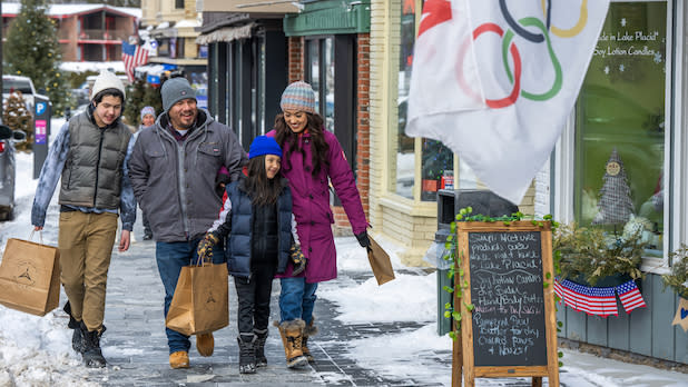 A family of four strolls down Lake Placid's snowy Main Street