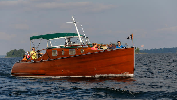 A group of people tour the St. Lawrence River aboard a wooden antique boat