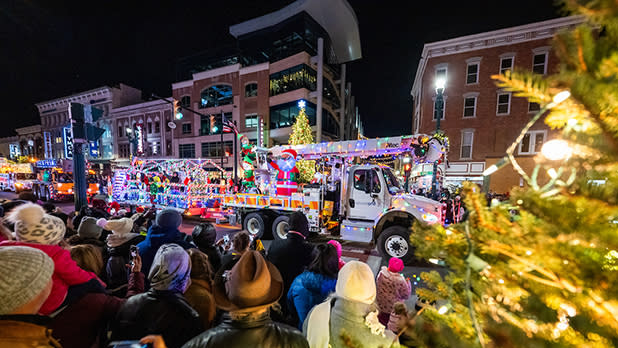 Crowds watch as a fire truck decorated in string lights and a Christmas tree participates in the the Schenectady Holiday Parade