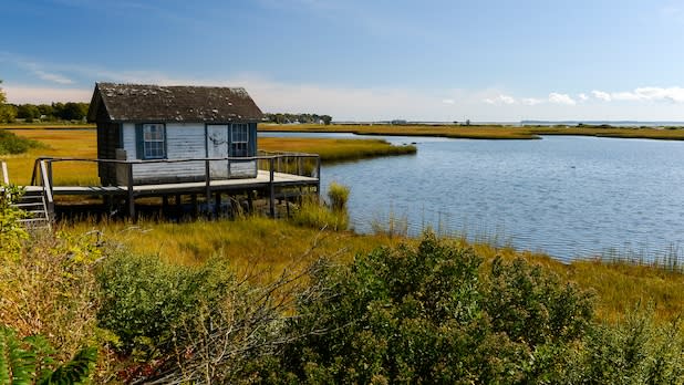A small house looks out over a body of water and wetlands along the North Fork Trail Scenic Byway