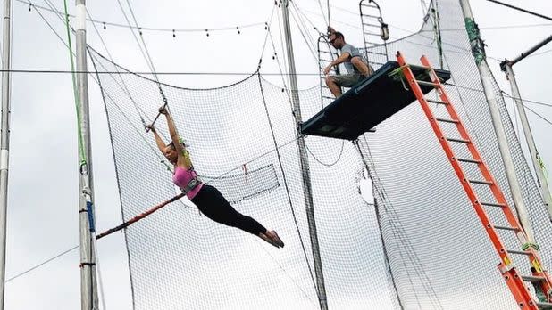 A person flying through the air on a trapeze surrounded by netting