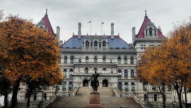 Exterior of the NYS Capitol building with orange trees lining the front steps to the entrance