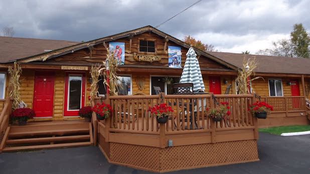 exterior of a log cabin-cabin style lodge with red doors and a front porch