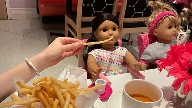 A woman places a French fry in front of an American Girl doll during a meal at the American Girl Cafe