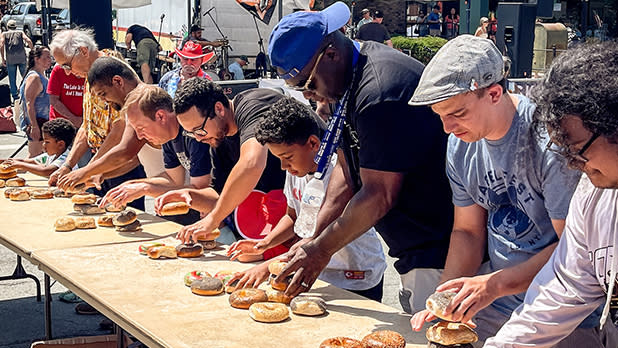 A group of people compete in a bagel stacking competition at The Bagel Fest in Monticello.