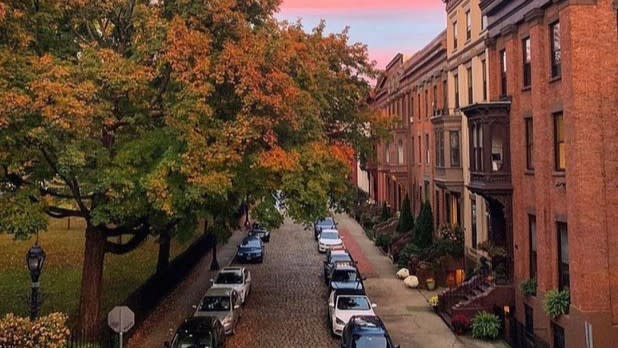 Sunset over the cobblestone streets lined with historic buildings and trees with fall colors