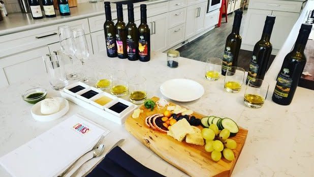 A spread of various cheeses, fruits, vegetables, and wine samples on a white counter top at Inns of Aurora Aurora Cooks! Class