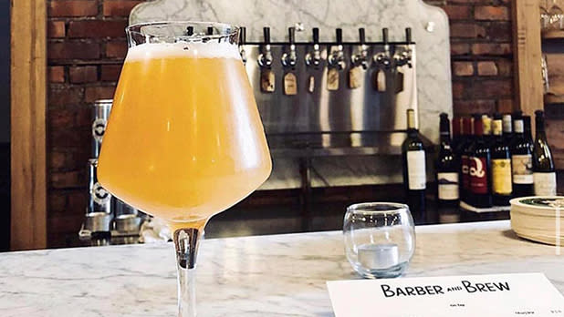 A glass of beer sits atop the marble bar at Barber and Brew