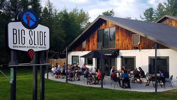 People sit at tables on the outdoor patio at Big Slide Brewery & Public House